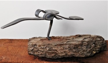 bird made of metal on wood chunk